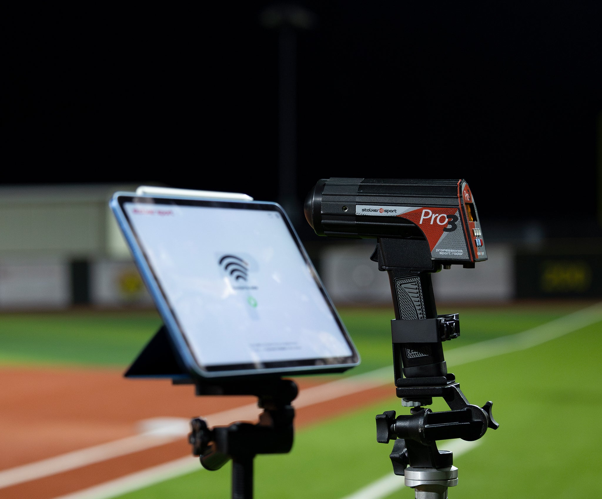 A Stalker Sport Pro 3 radar gun in a tripod mount next to an iPad on a tripod connecting to the Stalker Sport Radar iOS app.