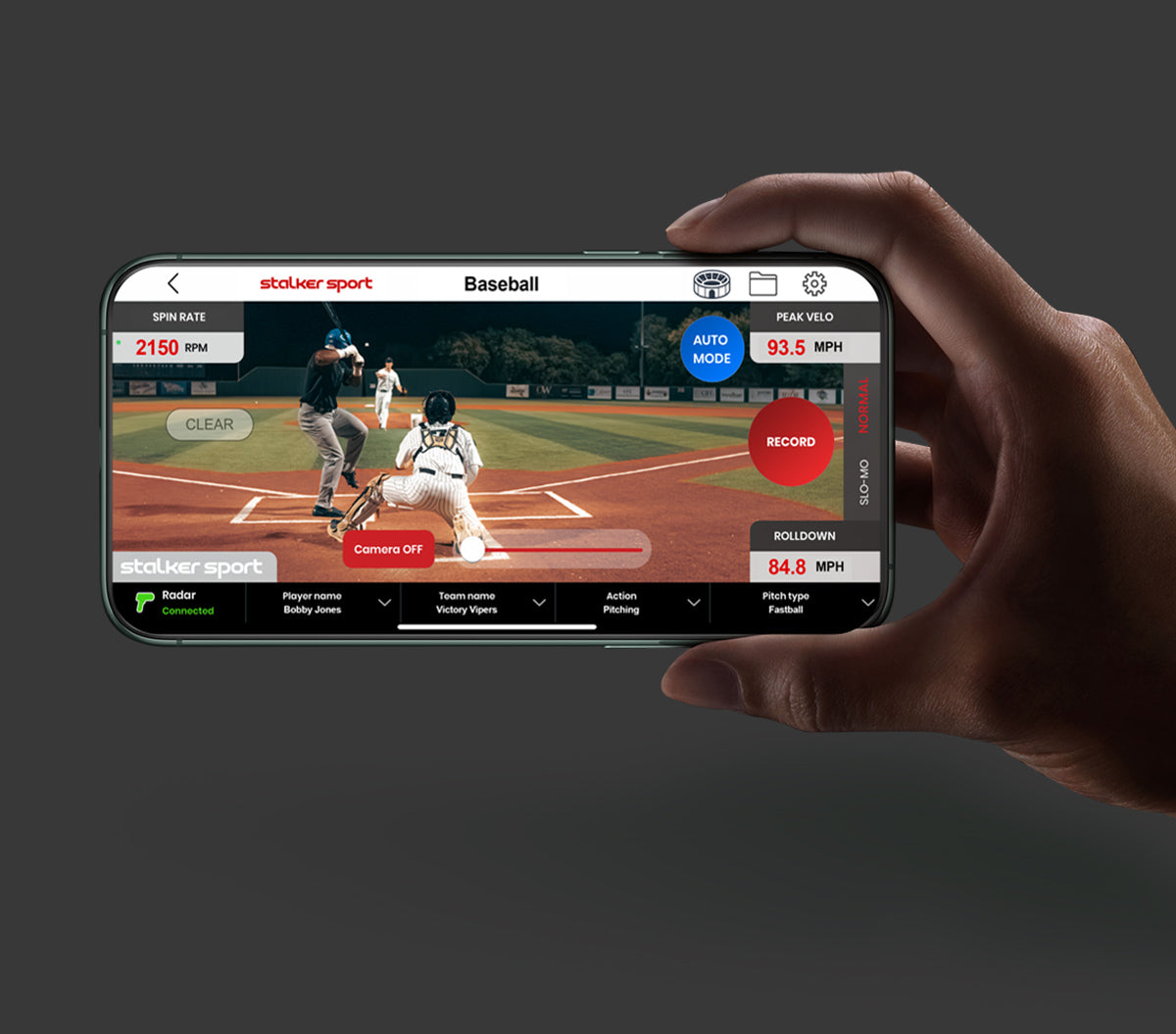A hand holding a phone showing the video mode of the Stalker Sport Radar iOS app showing 3 people playing baseball.