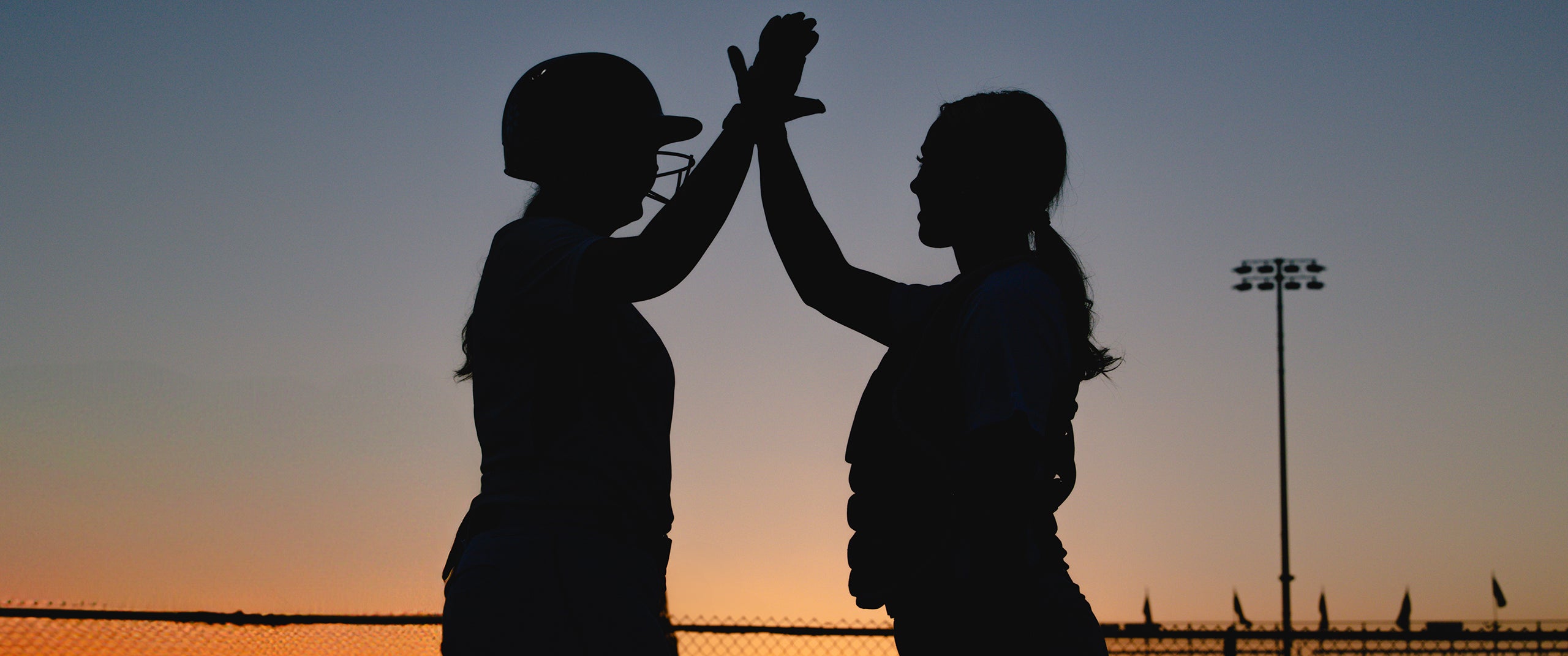 Two softball players from Team Stalker Sport giving each other a high five.