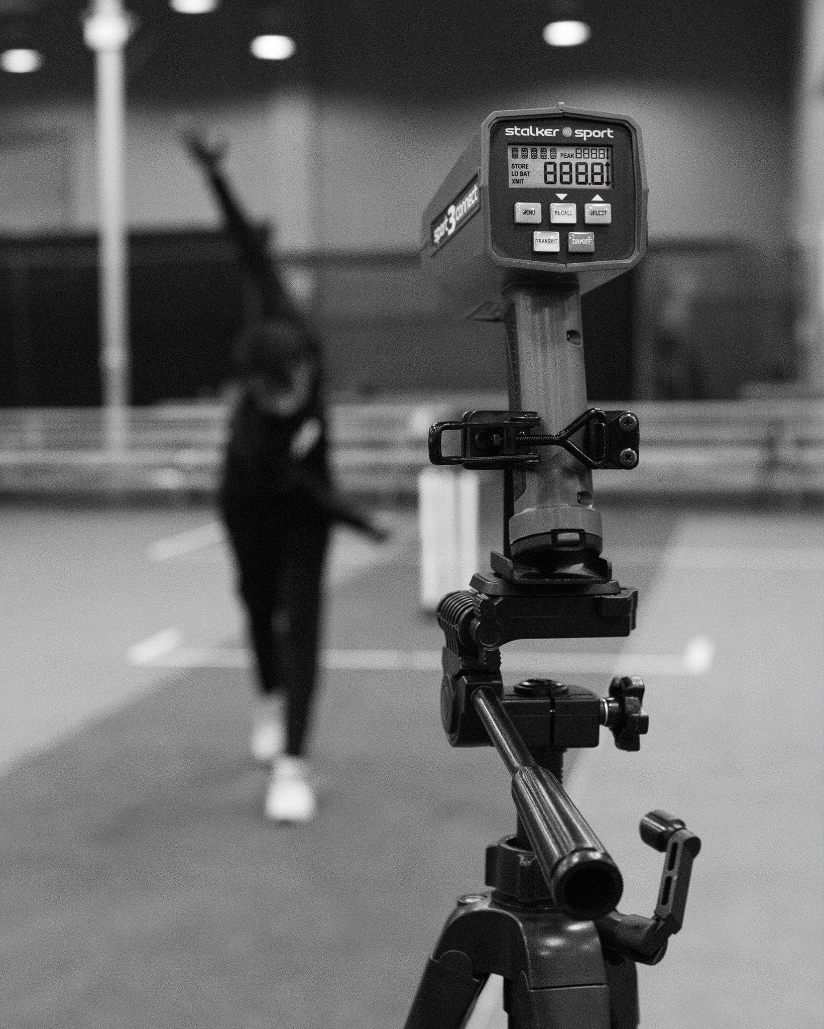 A tripod-mounted Sport 3 Connect radar gun measuring bowling speed in a cricket training facility.