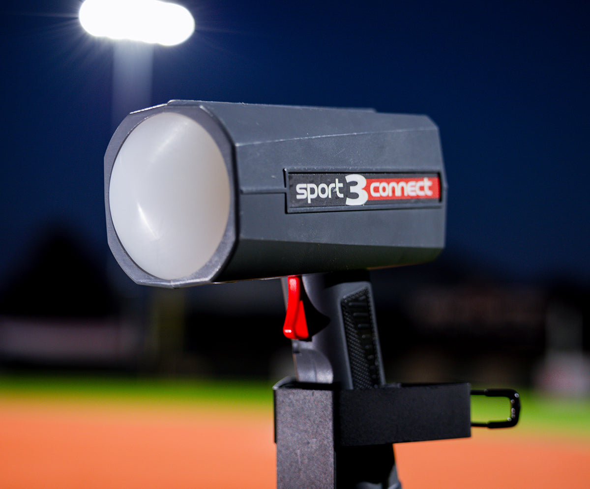 A Sport 3 Connect radar gun in a tripod mount with a baseball field in the background.