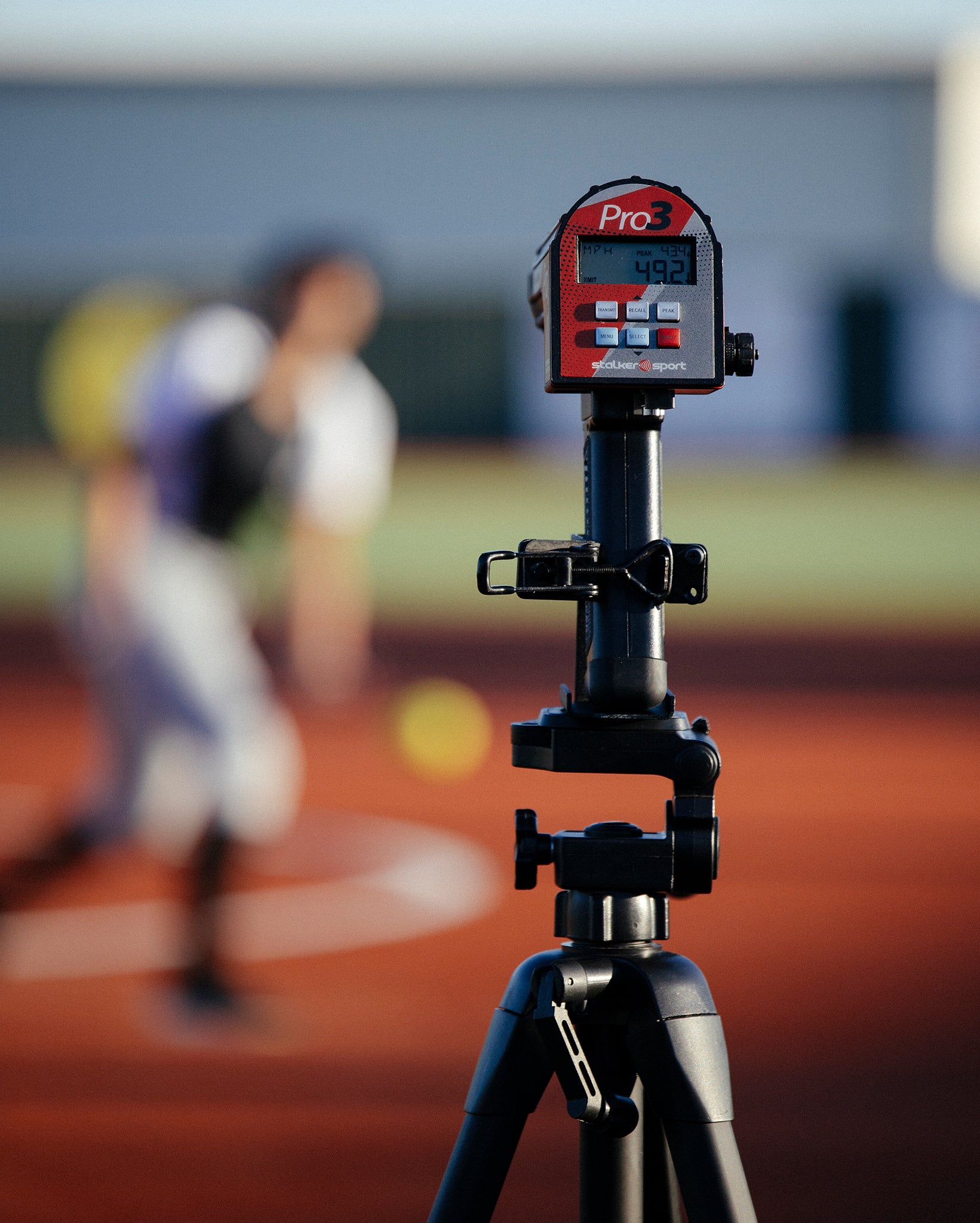 A Stalker Sport Pro 3 mounted on a tripod in the foreground with a softball game in the background.