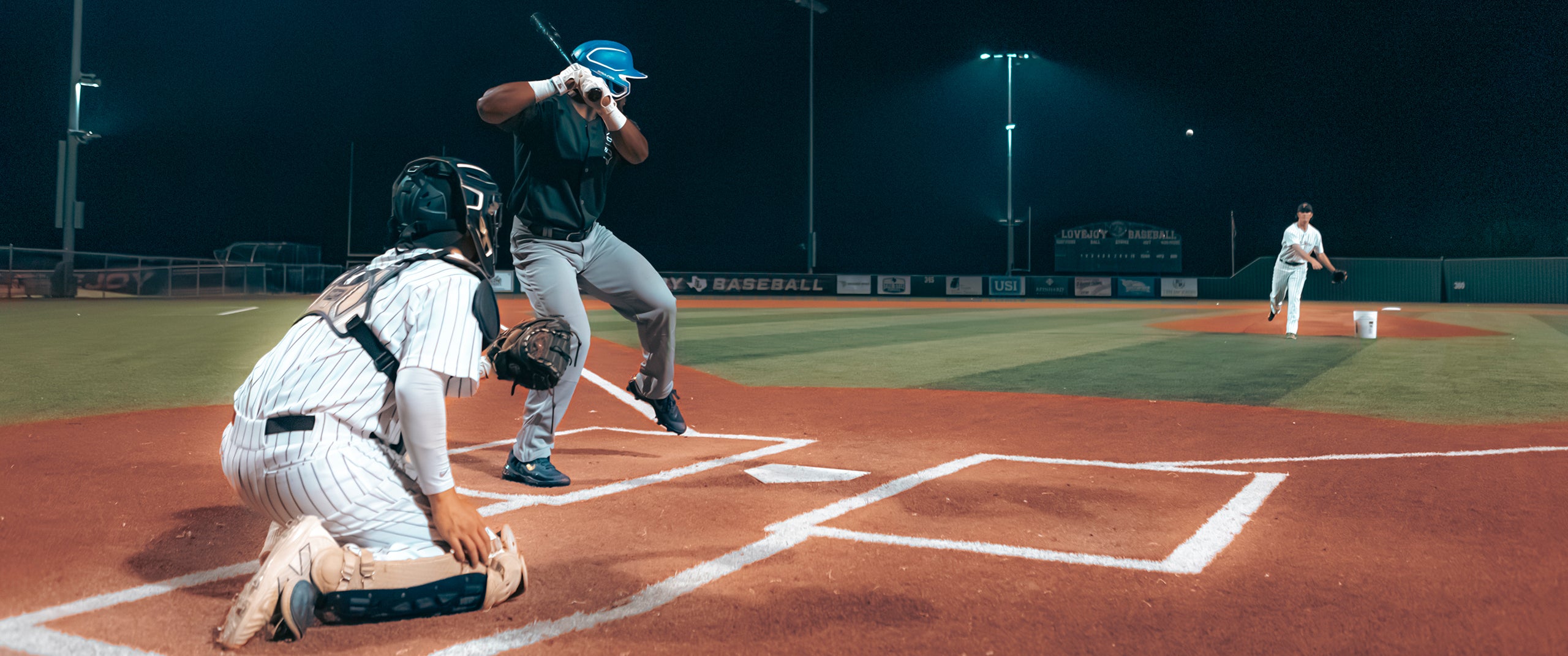 Three men from Team Stalker Sport playing baseball at night.