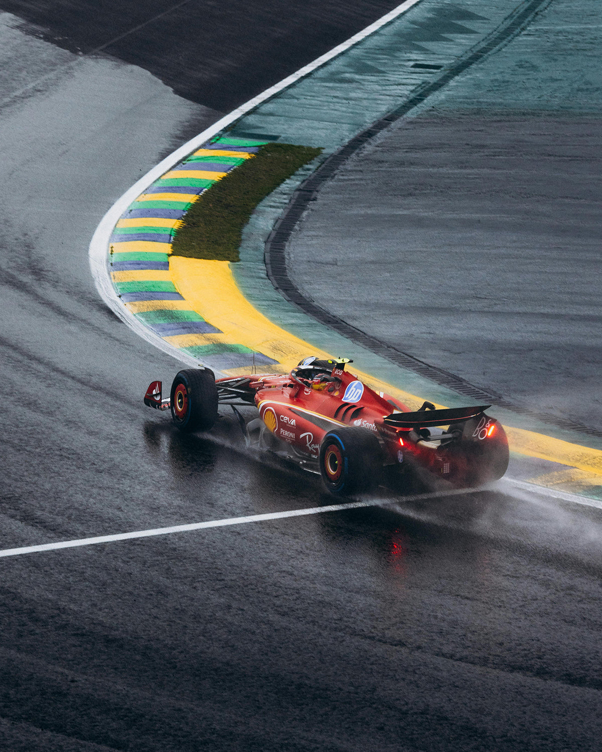 A red Formula 1 style car rounding a curve on a wet racetrack.