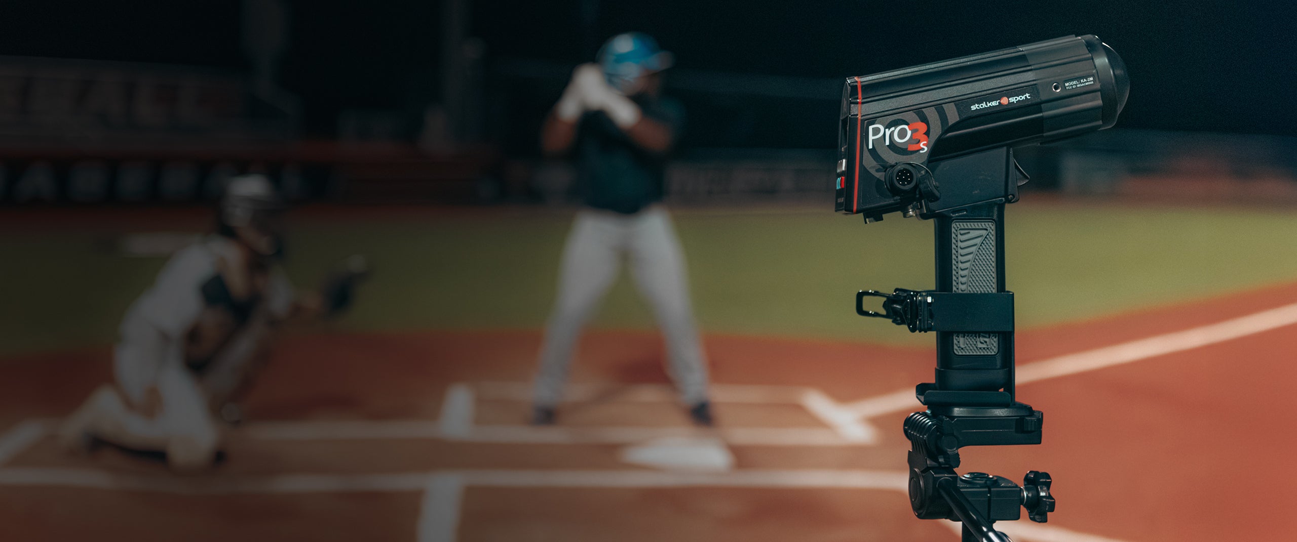 A Stalker Sport Pro 3s radar gun mounted on a tripod measuring spin rate and velocities at a baseball game at night. 
