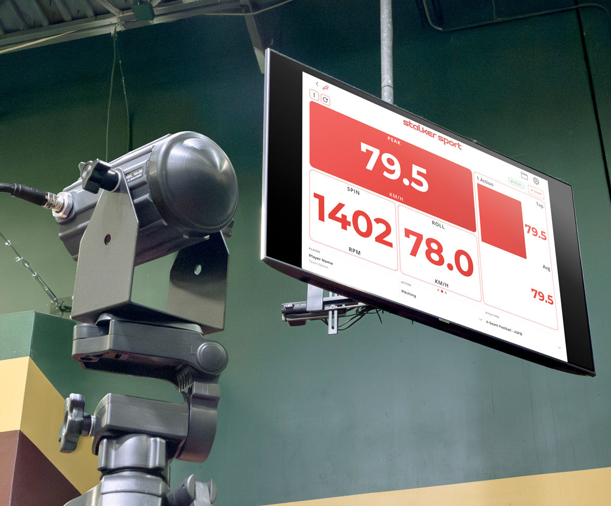 View of a baseball facility with a Stalker Sport Sensor 3s on a tripod mount nearby a television with the Stalker Sport App on the screen. 