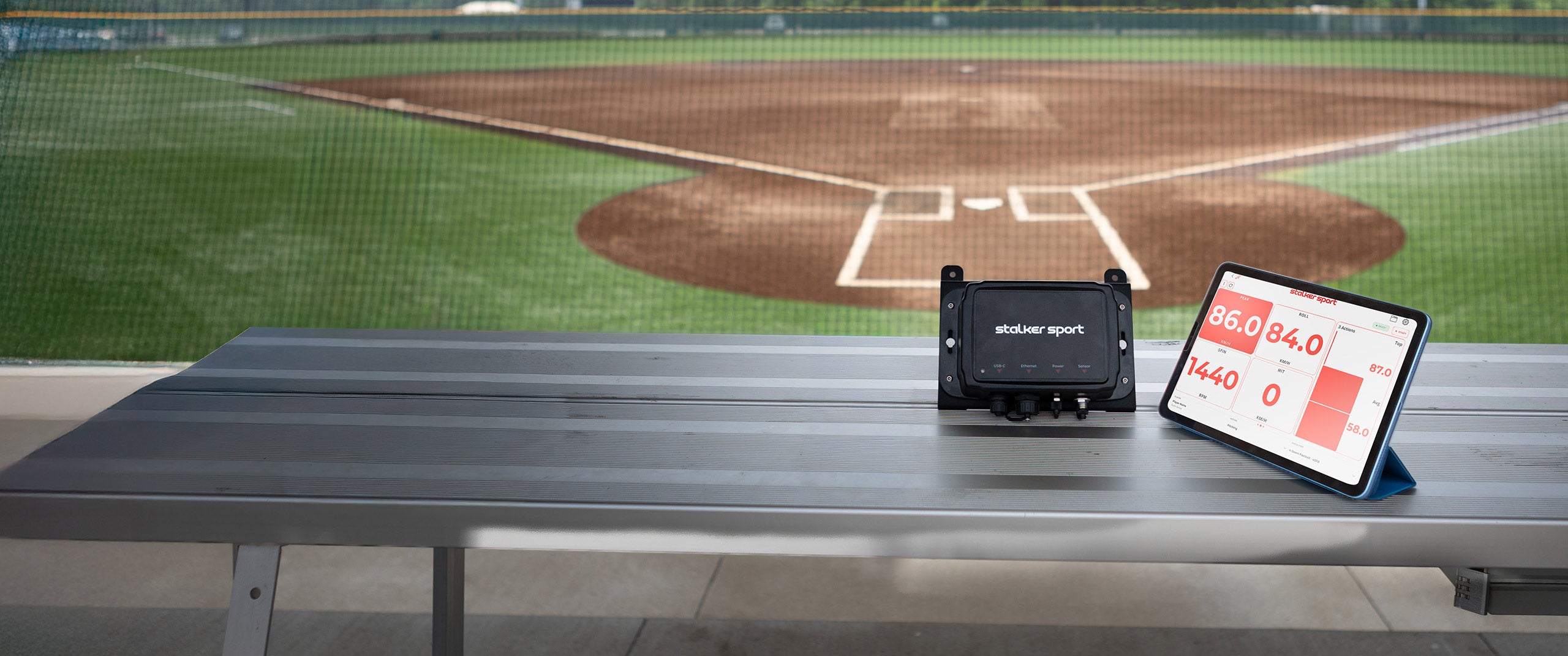 Stalker Sport Stadium Hub with Stalker Sport App on tablet, showcased on the bench at a ballpark.