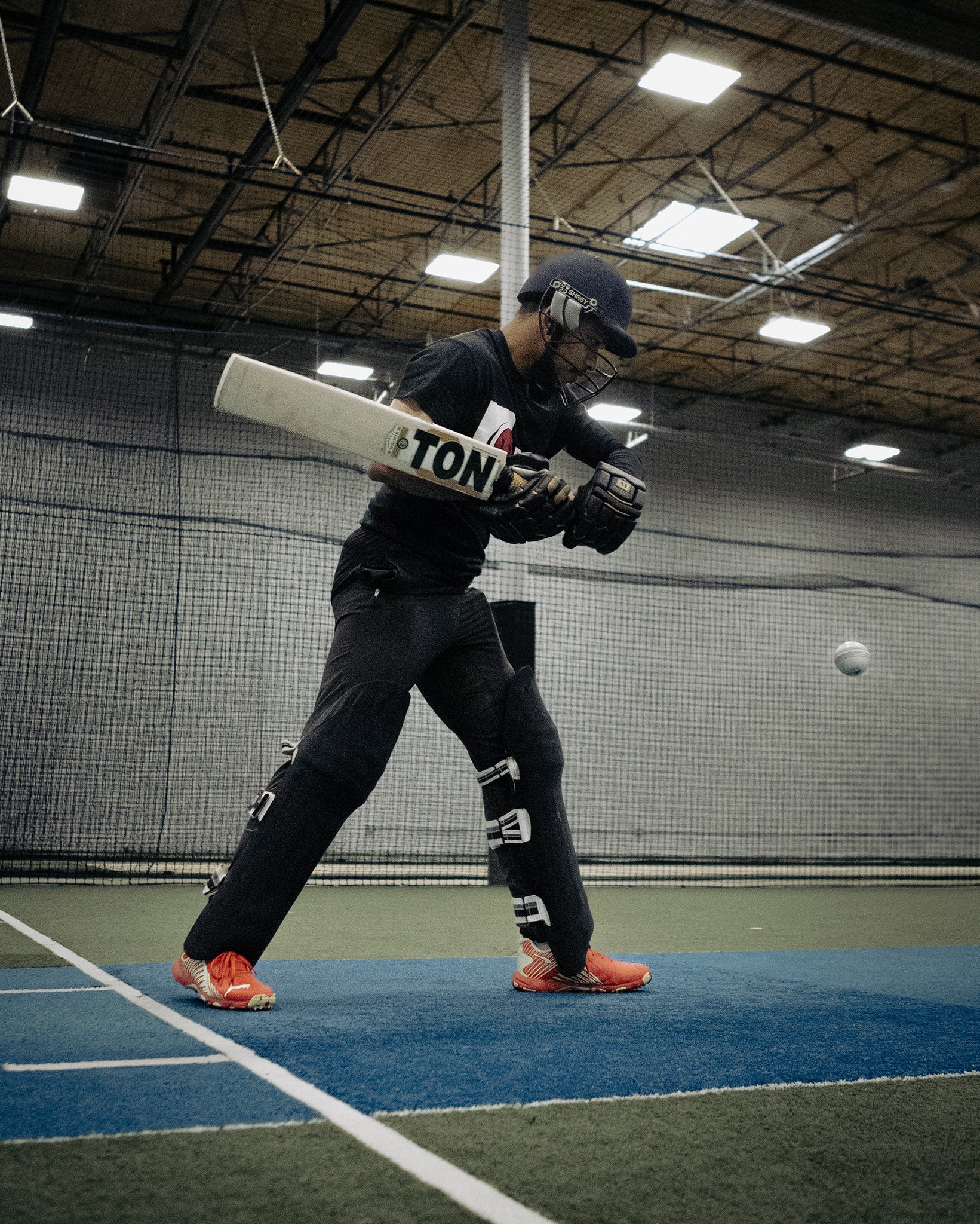 A cricket player hitting a pitch inside a training facility.