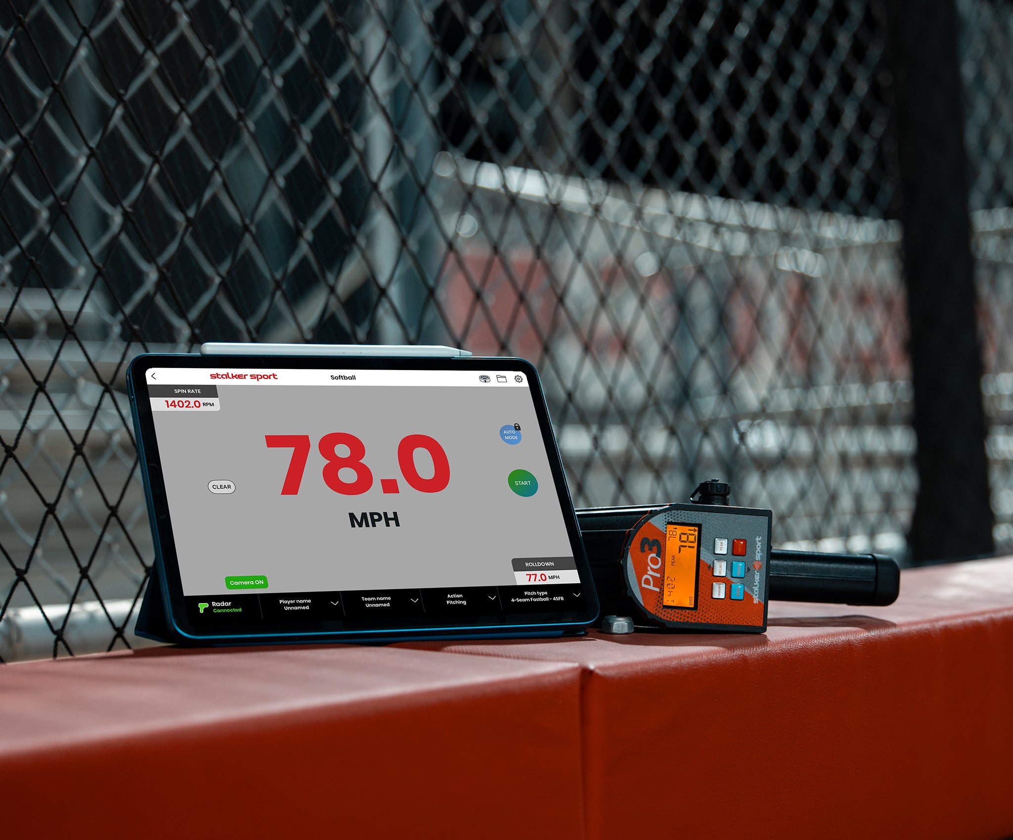 An iPad displaying the Stalker Sport Radar app next to a Pro 3 radar gun on a wall at a baseball field. 